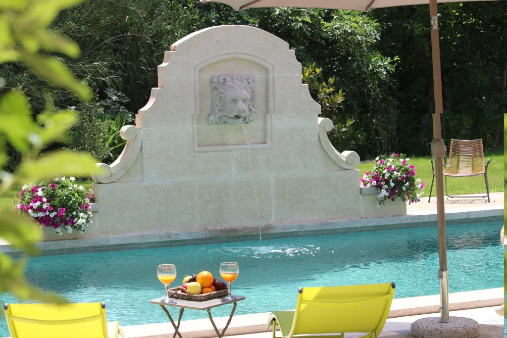 una fontana nel mezzo di una piscina con bicchieri da vino di La Bastide des Cyprès a Maussane-les-Alpilles