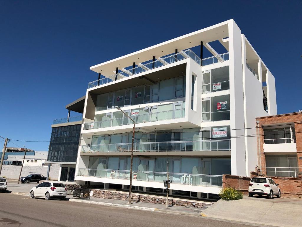 un bâtiment blanc avec des voitures garées devant lui dans l'établissement "Ninfas", à Puerto Madryn