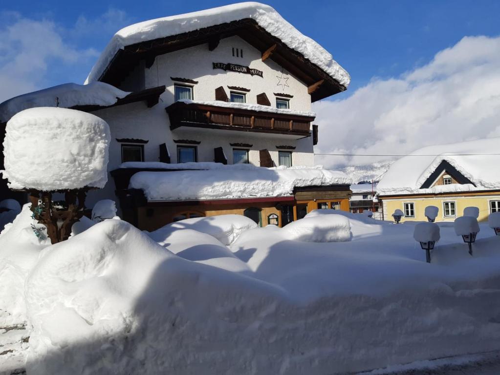 una casa cubierta de nieve delante en Pension Restaurant Meran en Abtenau