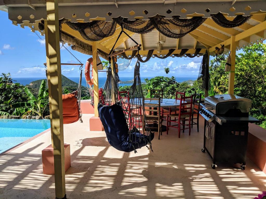 eine Terrasse mit einem Tisch, Stühlen und einer Hängematte in der Unterkunft Black Pearl Estate Villa in Gros Islet