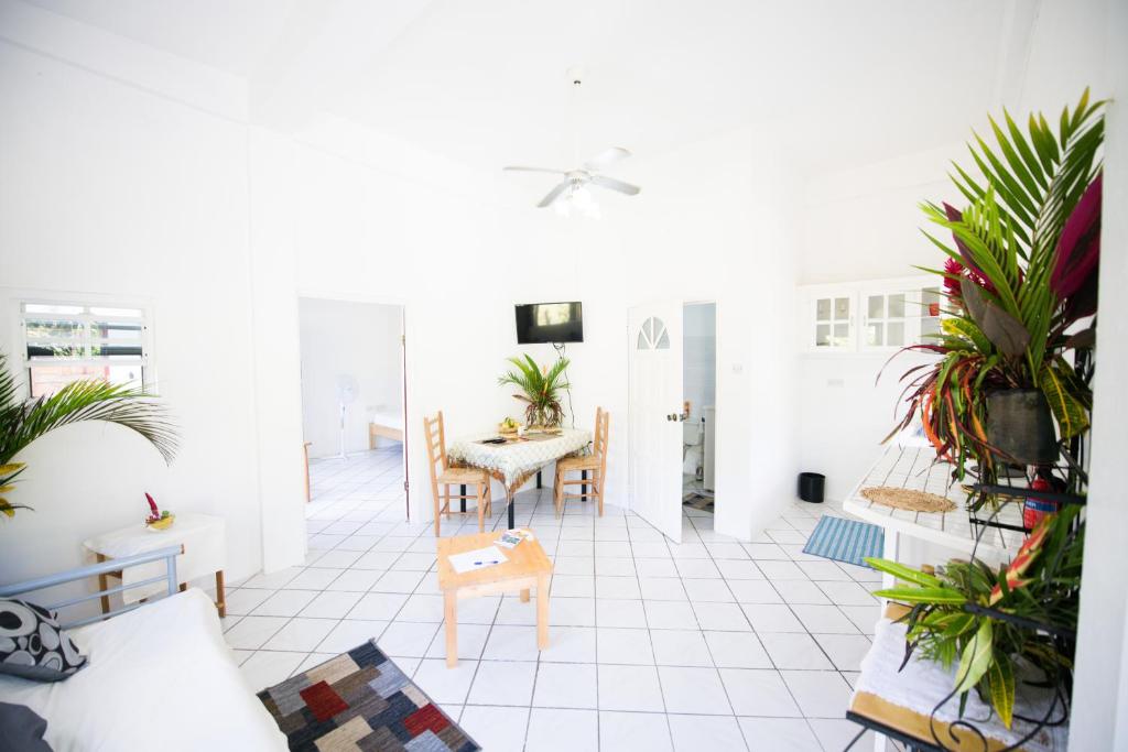 een woonkamer met witte tegelvloeren en planten bij Diamondview in Soufrière