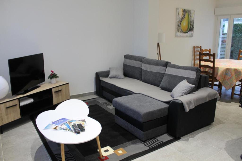 ein Wohnzimmer mit einem Sofa und einem TV in der Unterkunft "Mi-a-clo" in Cucq