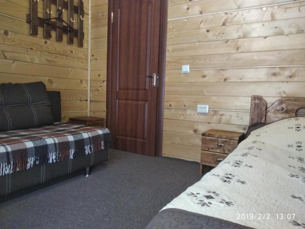Un dormitorio con una cama y una pared de madera. en Mandrivnyk, en Mykulychyn
