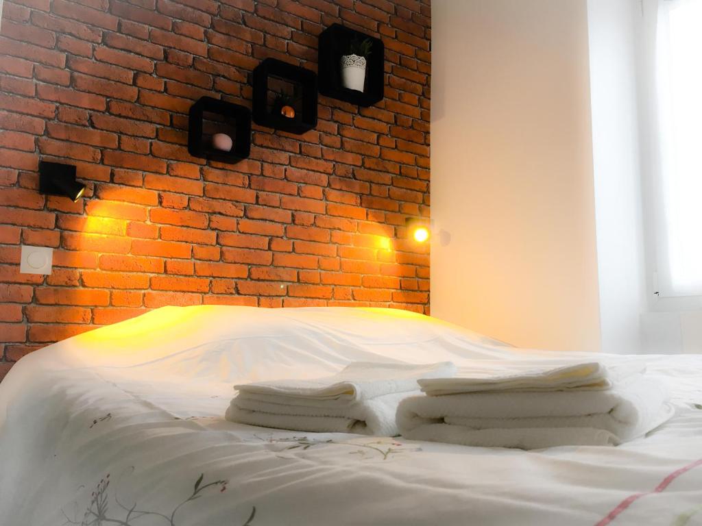 a bedroom with a brick wall and a white bed at SWEET APARTMENT CARRIERES - 1 chambre - 4 Pers - Wifi in Carrières-sur-Seine