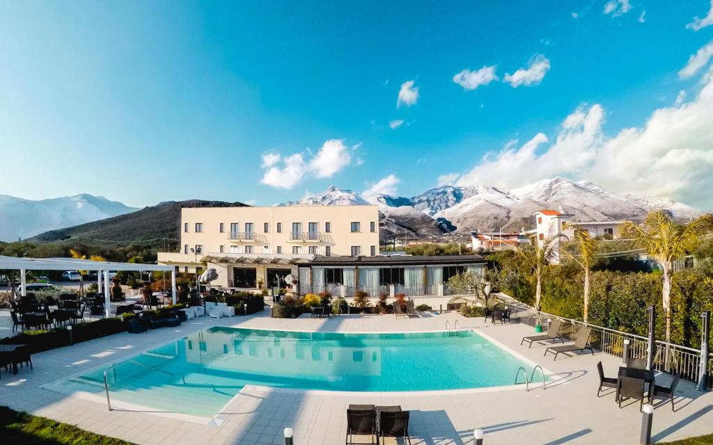 un complexe avec une piscine et des montagnes en arrière-plan dans l'établissement Kora Park Resort, à Formia