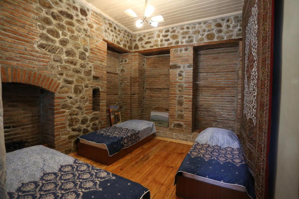 Habitación con 2 camas y pared de ladrillo en Ilham Mustafa Houses, en Sheki