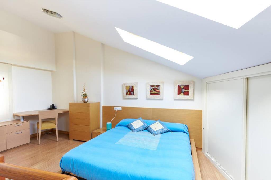 1 dormitorio con cama azul y escritorio en Bonito alojamiento en el centro historico, en Pamplona