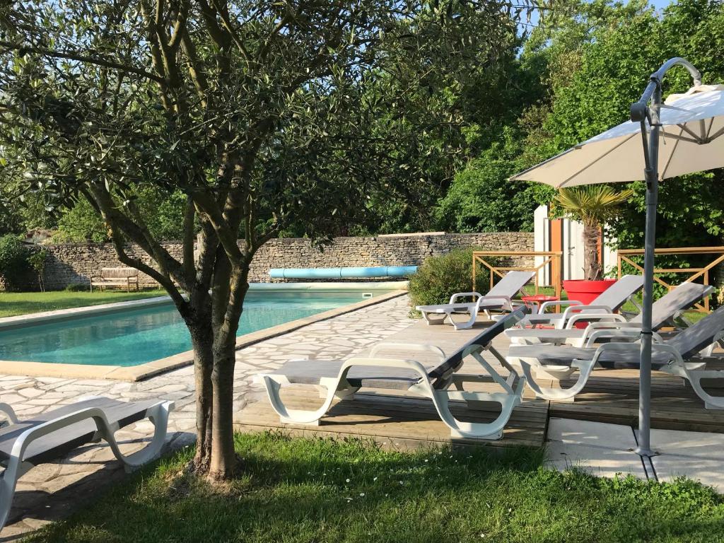 a group of lounge chairs and an umbrella next to a pool at Le Clos des Marais in Champagné-les-Marais