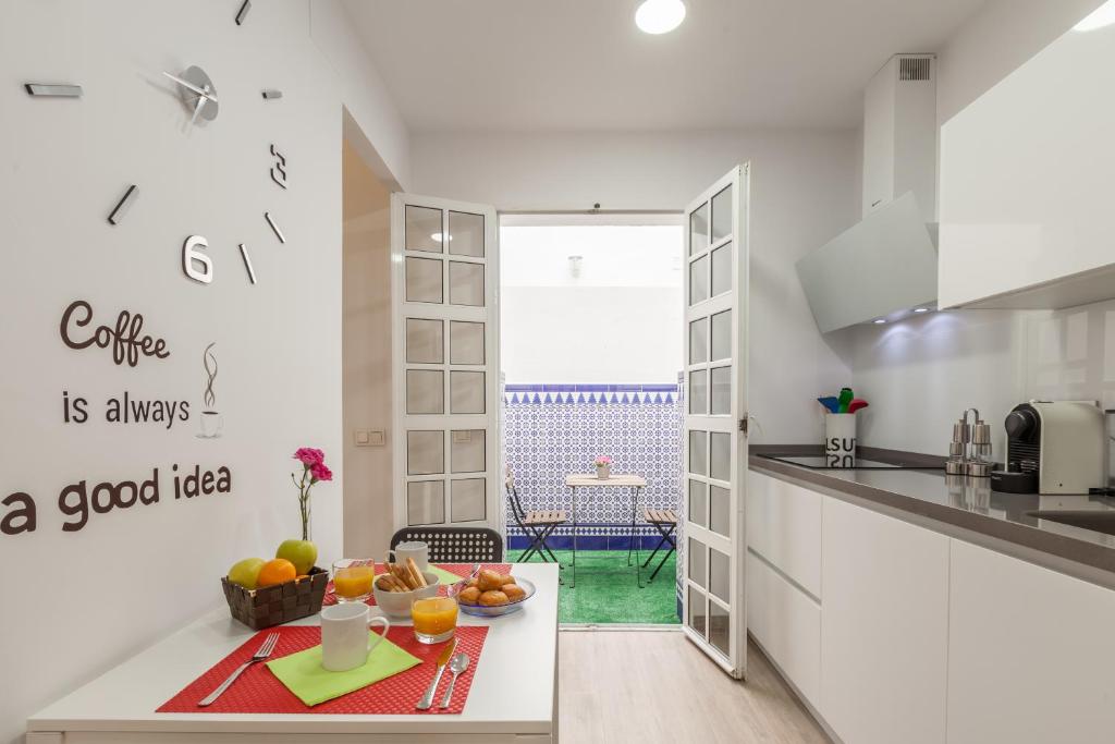 una cocina blanca con una mesa con fruta. en Casa de la Moneda - Center Luxury Duplex en Sevilla