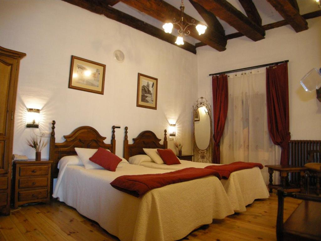 1 dormitorio con 2 camas y espejo en La Posada de Carmen, en Chañe