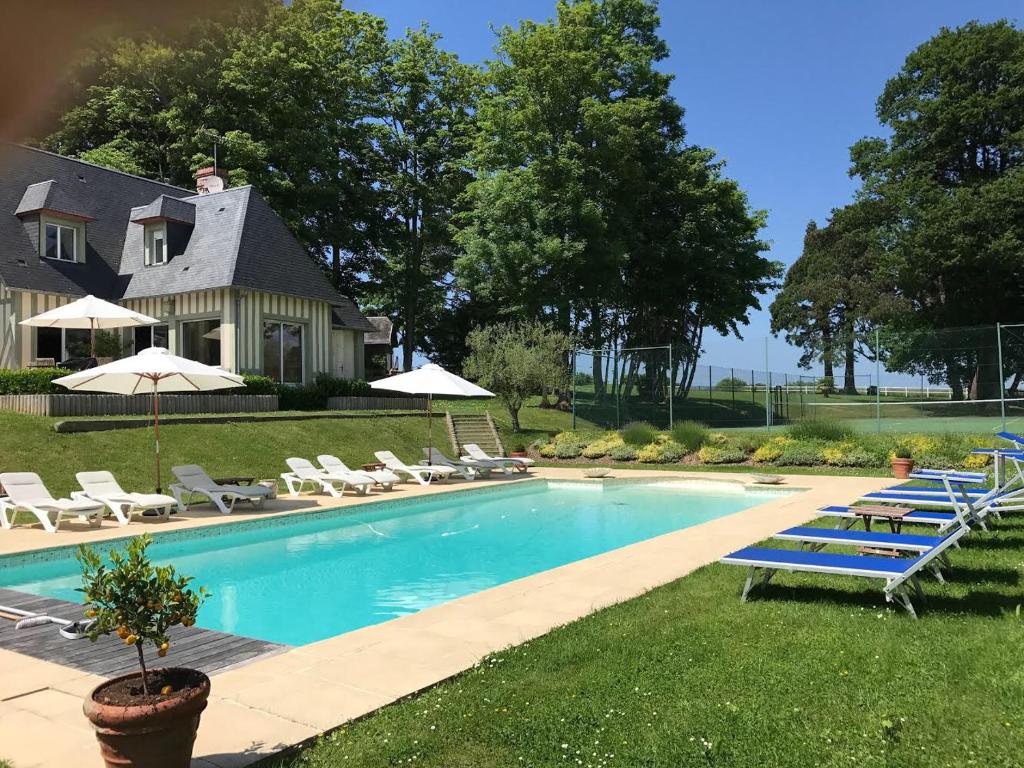 - une piscine avec des chaises et des parasols en face d'une maison dans l'établissement Superbe Villa Individuelle avec Piscine et Tennis privatifs, à Villers-sur-Mer