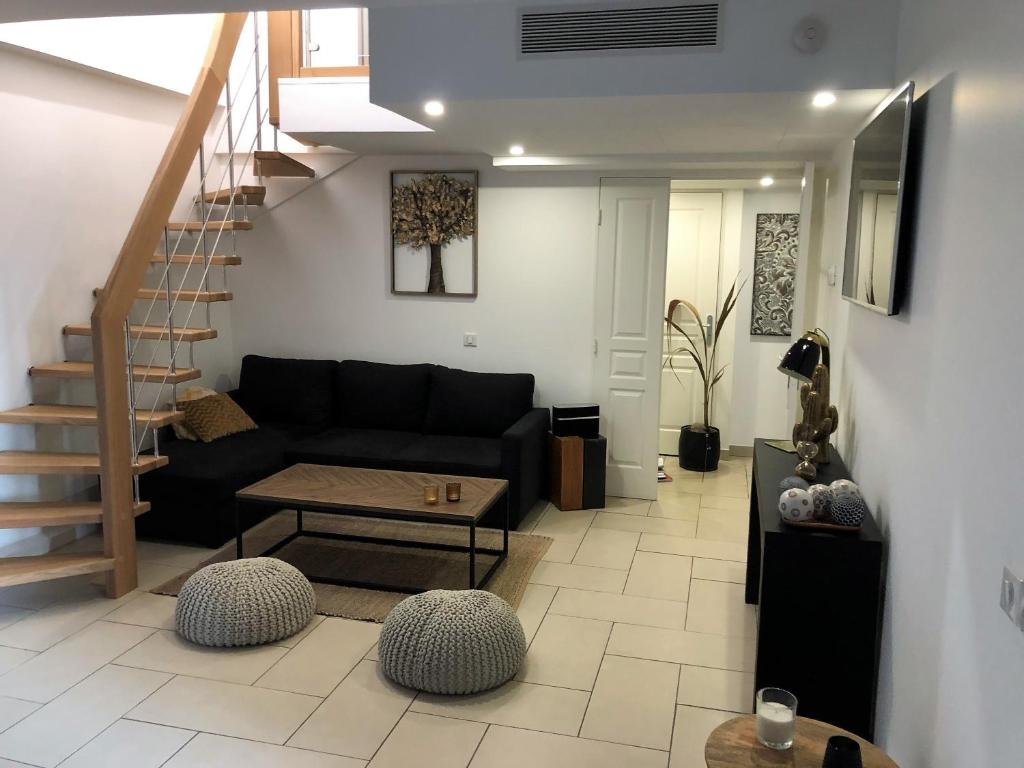 a living room with a black couch and a staircase at 10 Rue de la Rampe in Cannes