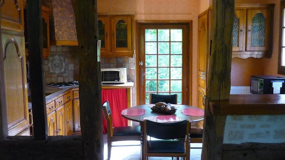 une cuisine avec une table et des chaises dans l'établissement La martinière - Au cours du ruisseau, à Saint Germain de Livet