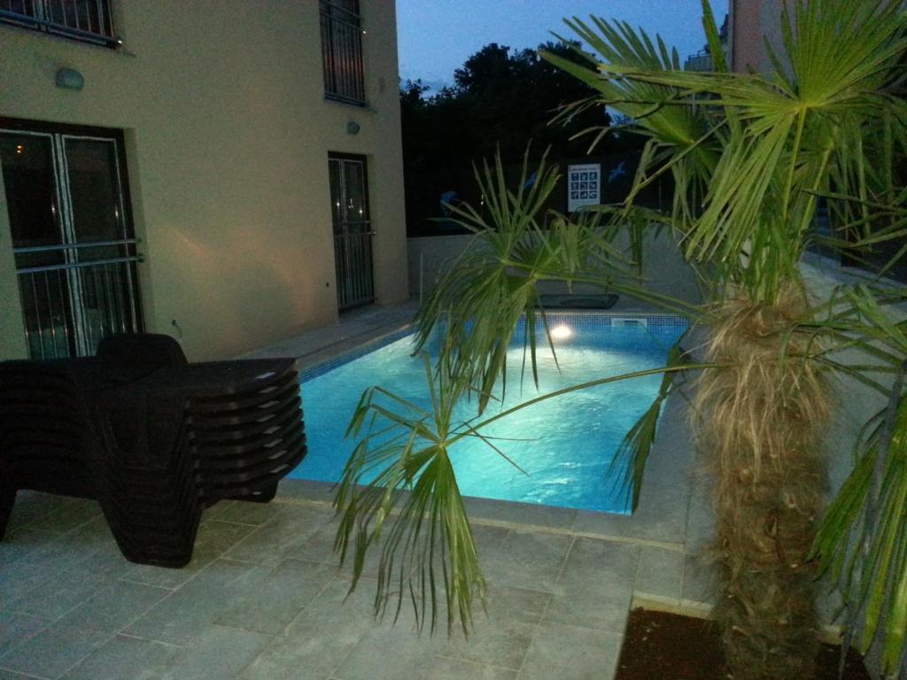 uma piscina com duas palmeiras ao lado de um edifício em Apartments Jukić em Porec