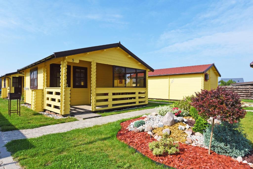 a yellow house with a garden in front of it at Poilsio nameliai Gulbes takas in Šventoji