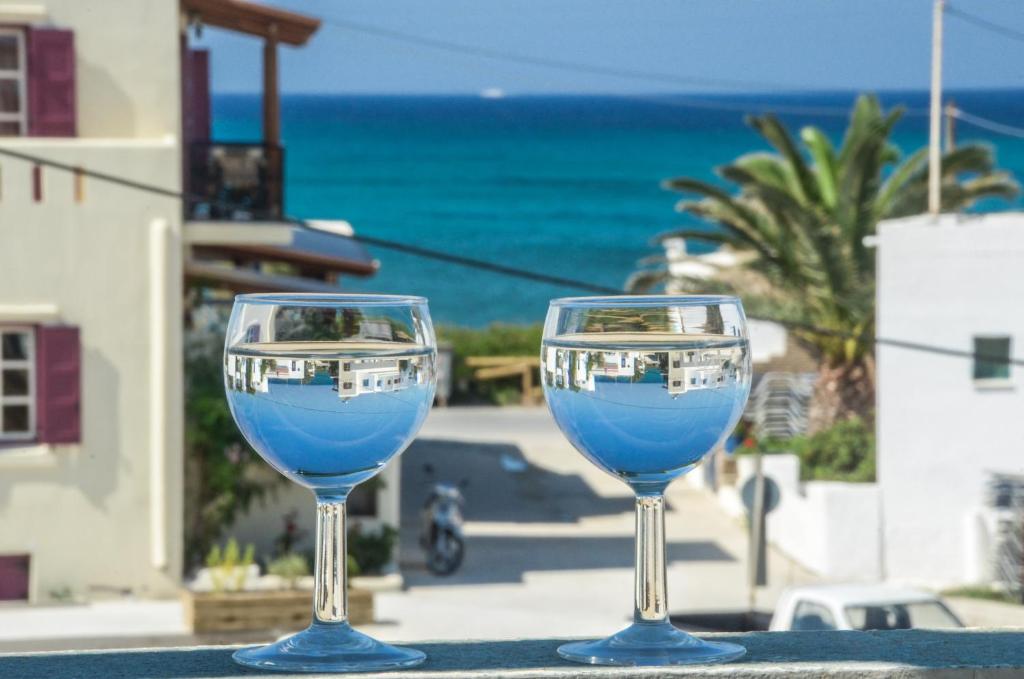 dos copas de vino sentadas en una mesa con el océano en el fondo en Sunday Studios, en Agia Anna de Naxos