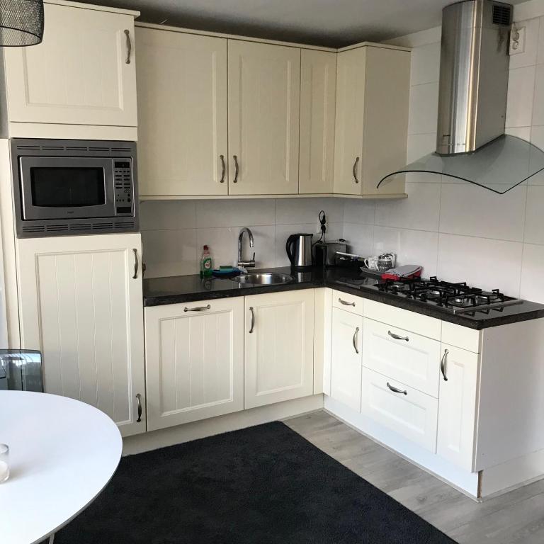 a kitchen with white cabinets and a microwave at Villa 't Haasduin in Wijk aan Zee
