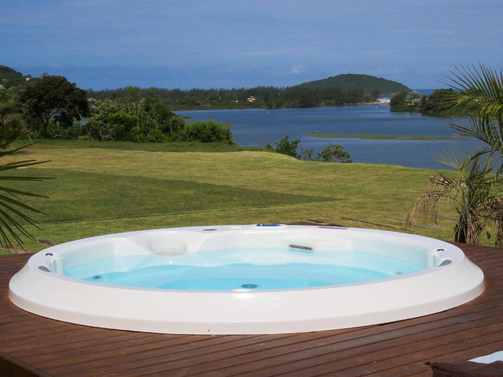 bañera de hidromasaje en una terraza con vistas al agua en Pousada Águas de Ibiraquera Suíte Luz, en Imbituba