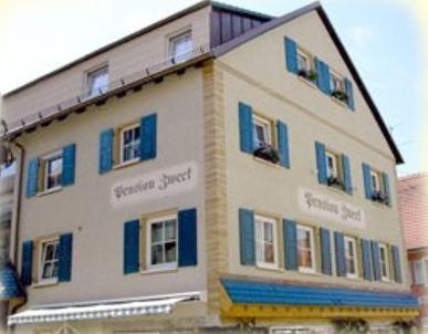 un gran edificio blanco con persianas azules en Pension Zweck, en Gössweinstein