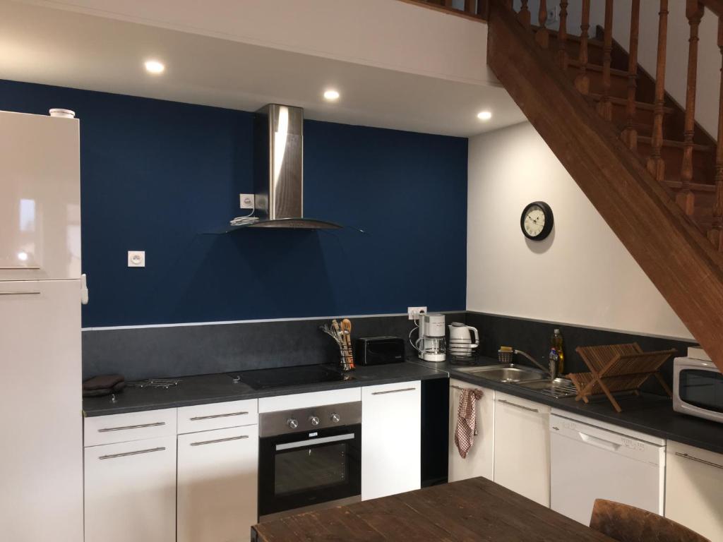 een keuken met witte kasten en een blauwe muur bij La cathare appartement in Lézignan-Corbières