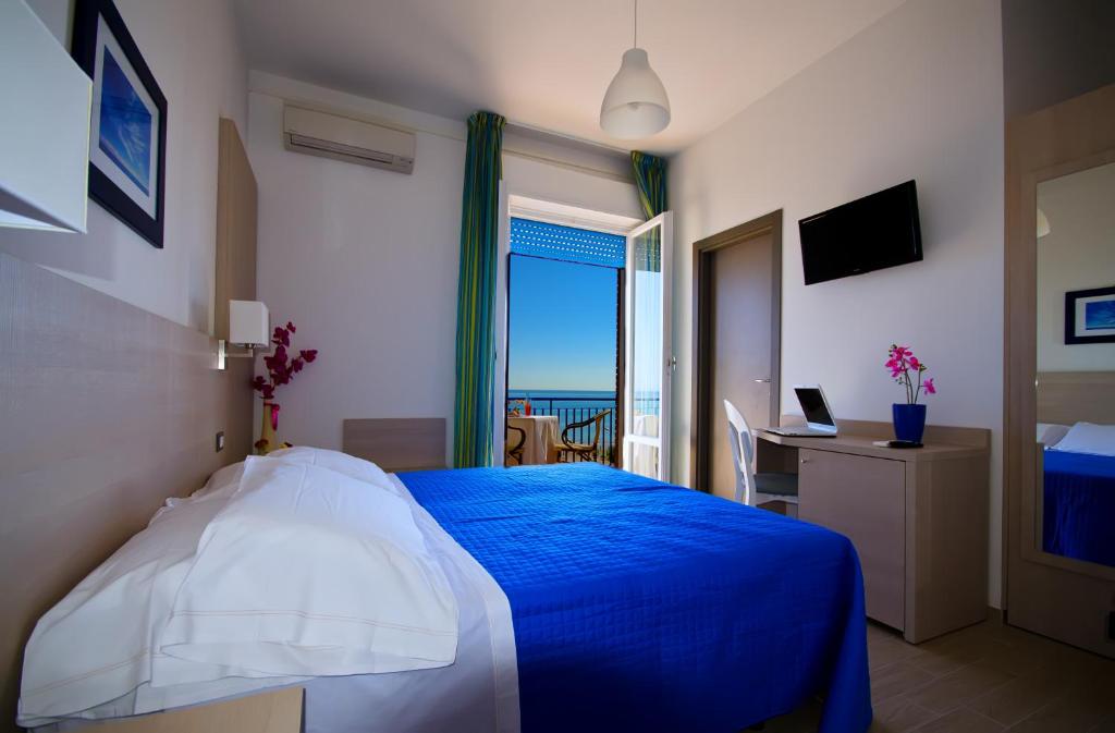 Schlafzimmer mit einem blauen Bett und Meerblick in der Unterkunft Hotel Olympia in Senigallia