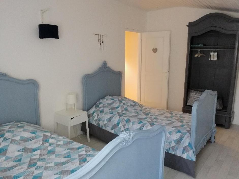 een slaapkamer met 2 bedden en een tafel met een nachtkastje bij Le Gîte du Cheval Blanc in Fraize