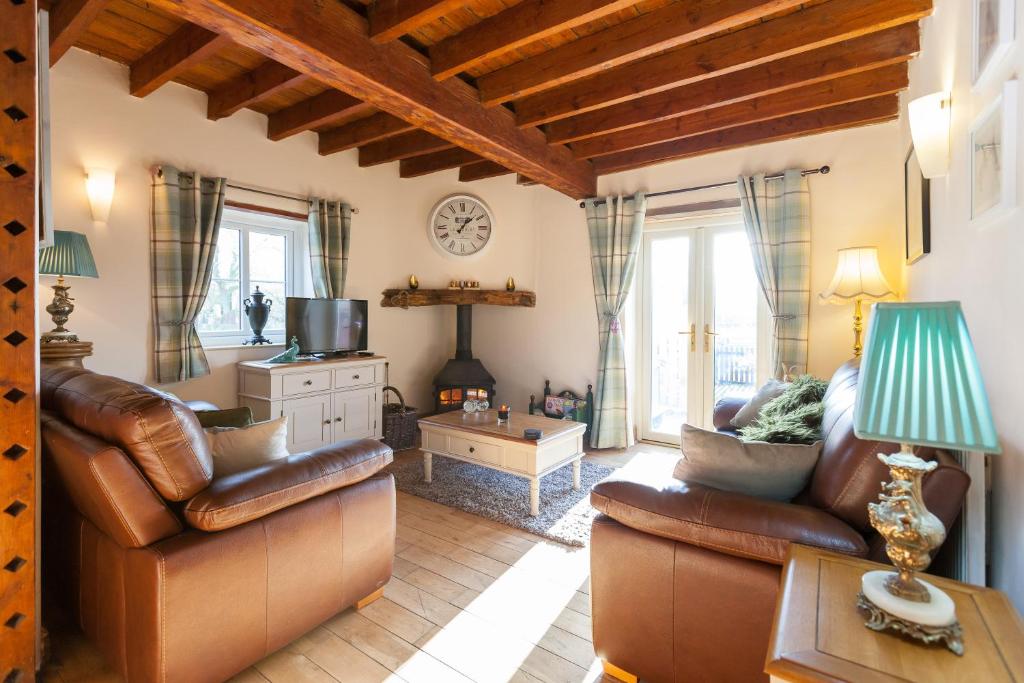 a living room with leather furniture and a table at Skipbridge Farm Cottages in Green Hammerton