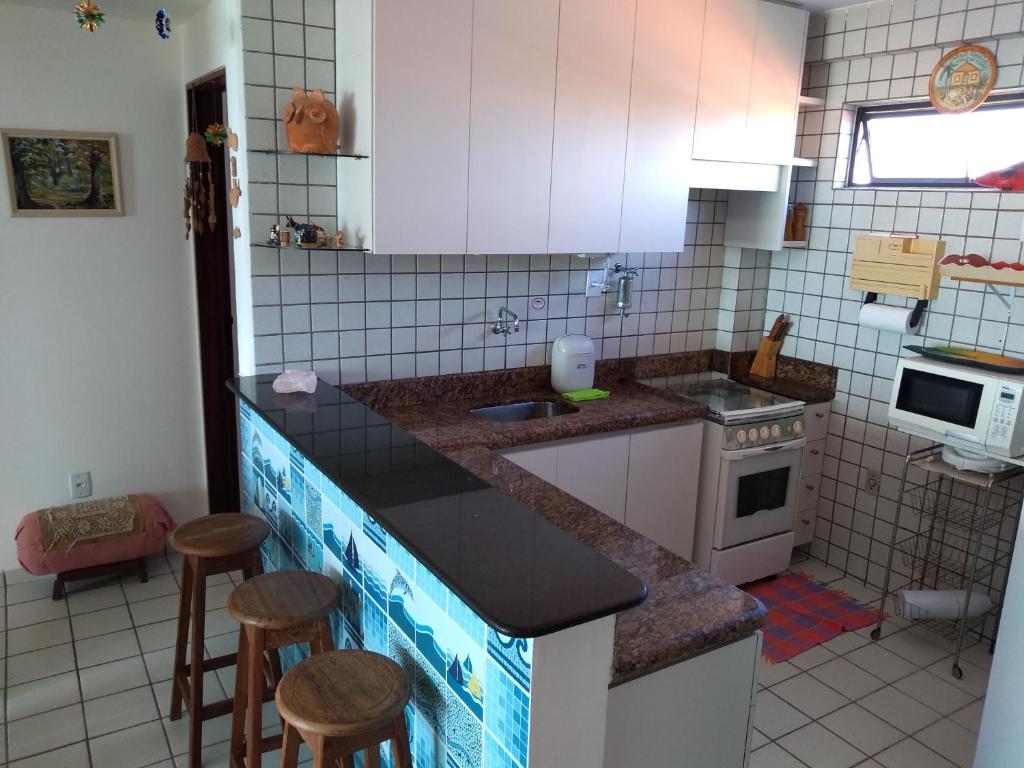 a kitchen with a sink and a counter with stools at Praia de Camboinha-PB apto bacana! in Cabedelo
