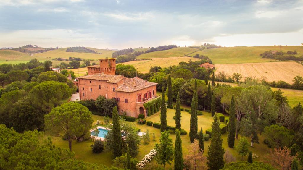 une vue aérienne sur une maison dans un champ arboré dans l'établissement Castello di San Fabiano, à Monteroni dʼArbia