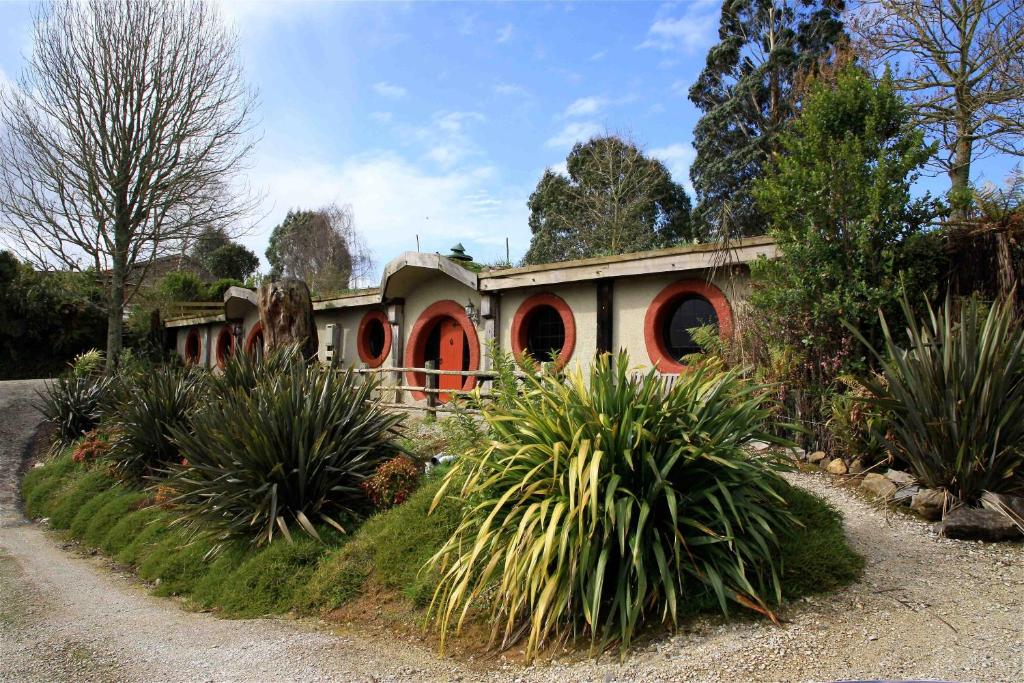 a house with red doors in a yard with plants at Woodlyn Park Motel in Waitomo Caves
