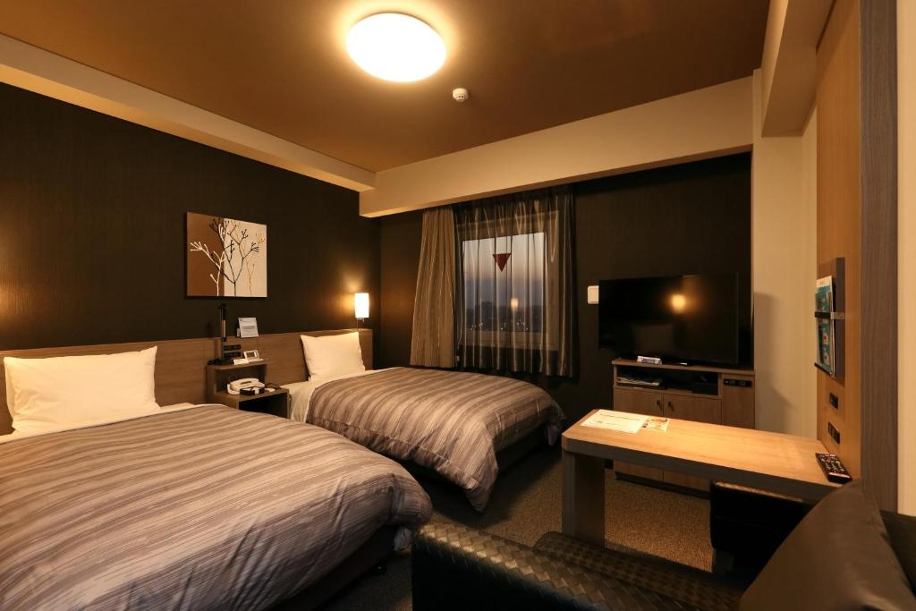a hotel room with two beds and a television at Hotel Route-Inn Shinshiro in Shinshiro
