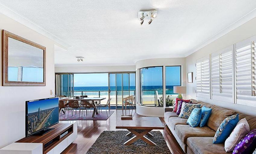 a living room with a couch and a television and a table at BEACHFRONT Beauty! in Gold Coast