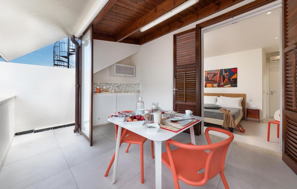 a kitchen and dining room with a white table and orange chairs at B&B Adduari in San Vito lo Capo