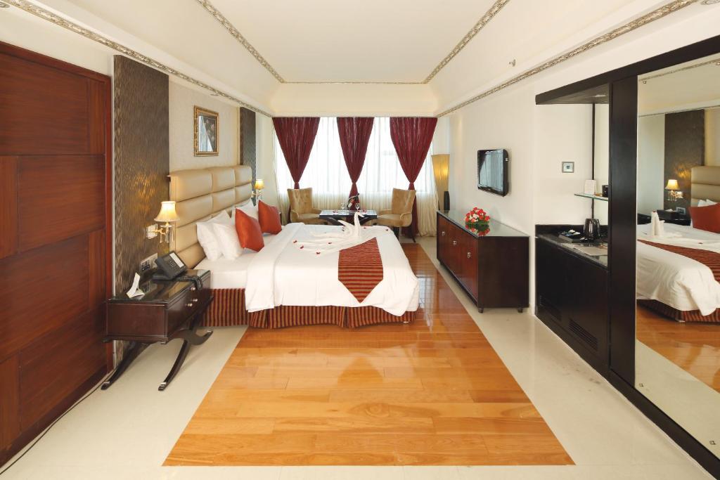 a large hotel room with a bed and a mirror at Windsor Rajadhani Hotel in Trivandrum