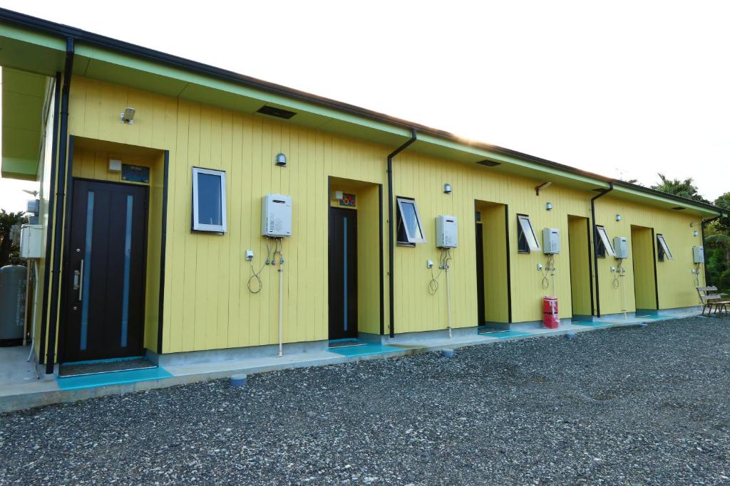 eine Reihe gelber Gebäude mit Fenstern und einem Hydranten in der Unterkunft Pension Kongo Baru in Tokunoshima