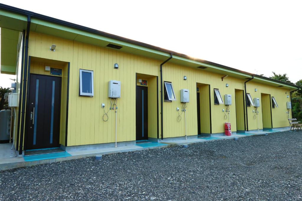 a row of yellow buildings with windows and a fire hydrant at Pension Kongo Baru in Tokunoshima