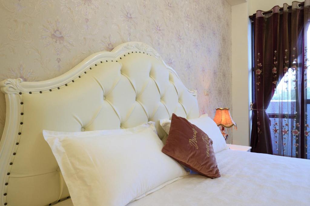 a white bed with a white headboard and pillows at 花蓮漫漫時光電梯包棟民宿 in Hualien City