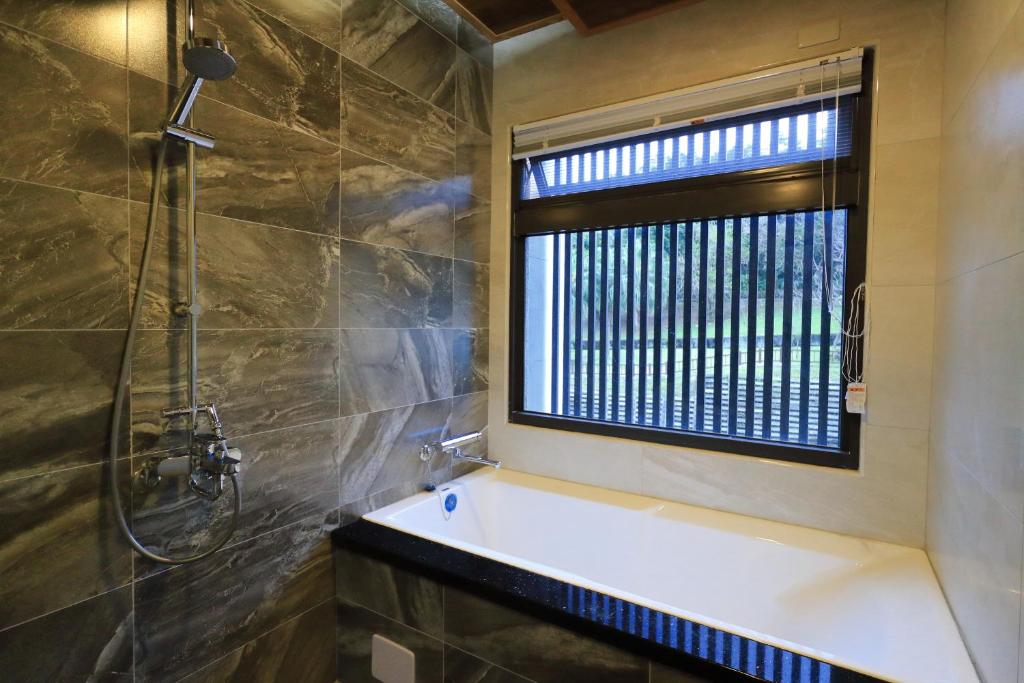 a bathroom with a bath tub and a window at 花蓮漫漫時光電梯包棟民宿 in Hualien City