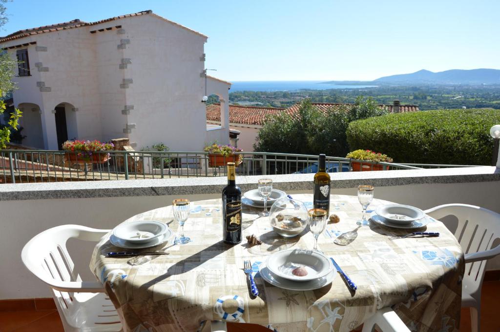 布多尼的住宿－Appartamento Li Puntiti 1，阳台上配有带葡萄酒瓶和玻璃杯的桌子