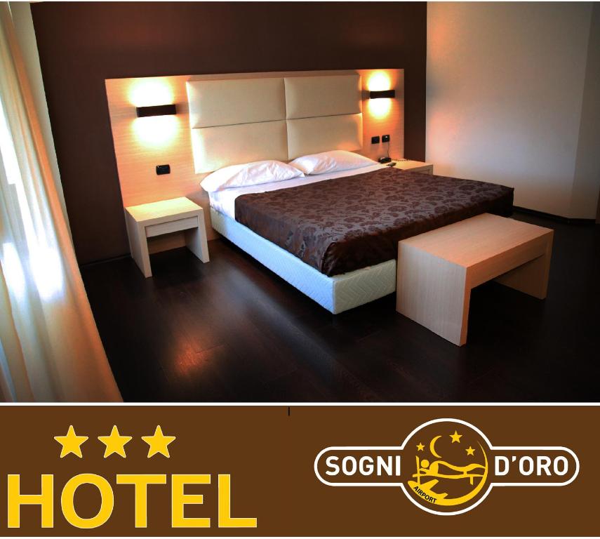 ラメーツィア・テルメにあるHotel Sogni D'Oro Airportのベッド1台とテーブル2台が備わるホテルルームです。