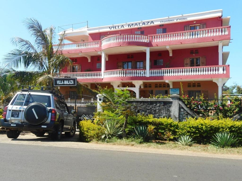 um jipe estacionado em frente a um edifício vermelho em Villa-Malaza em Antalaha