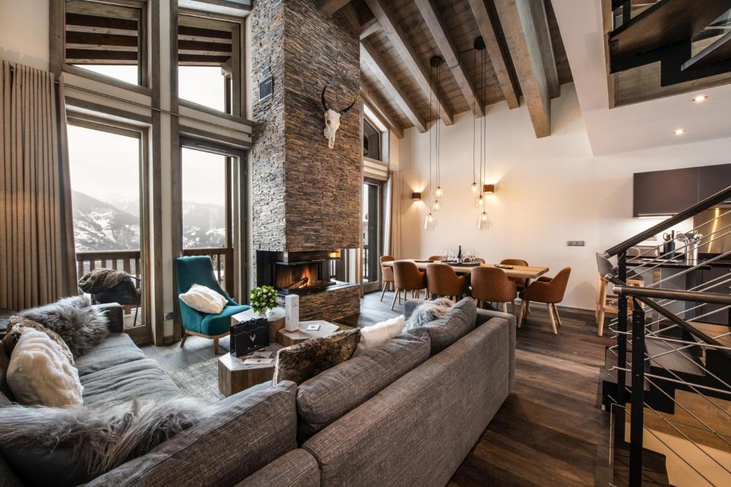 a living room with a couch and a dining room at Yellowstone Lodge by Alpine Residences in La Tania