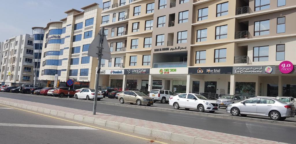 una strada con auto parcheggiate di fronte a un edificio di Al Shumoo Apparment a Mascate