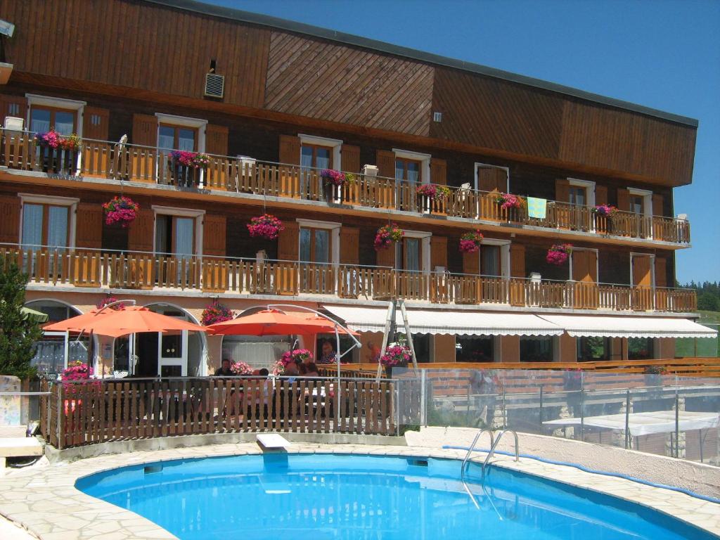 a hotel with a swimming pool in front of a building at Hôtel Notre Dame Des Neiges in La Féclaz