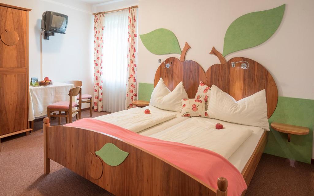 Schlafzimmer mit einem großen Bett mit einem Kopfteil aus Holz in der Unterkunft Wirtshaus Meißl in Puch bei Weiz