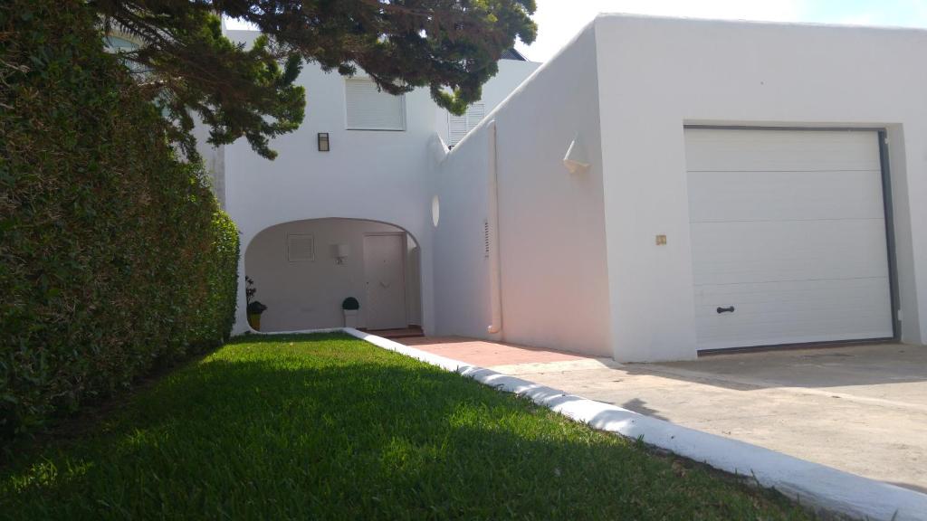 un edificio blanco con garaje y patio de césped en Casa Chafarinas, en Vera