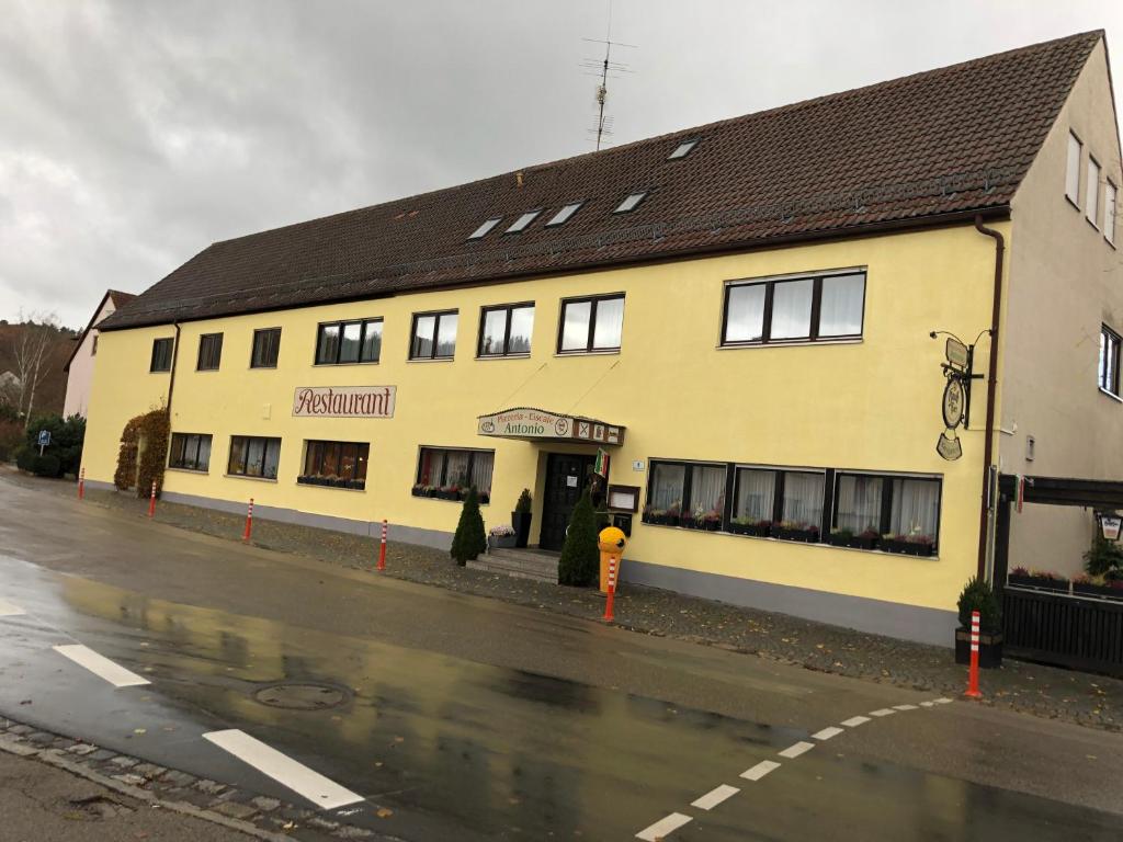 un edificio amarillo al lado de una calle en Eiscafé - Pizzeria Antonio, en Lichtenau