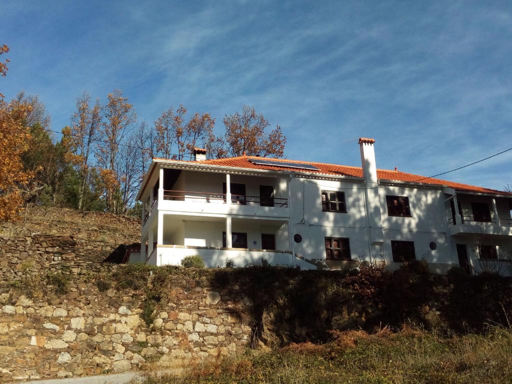 a white building with a red roof on a hill at Casa da Sicó in Manteigas