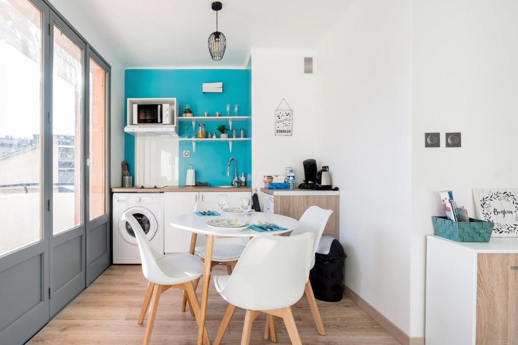 a kitchen with a table and white chairs at LP Anne in Annecy