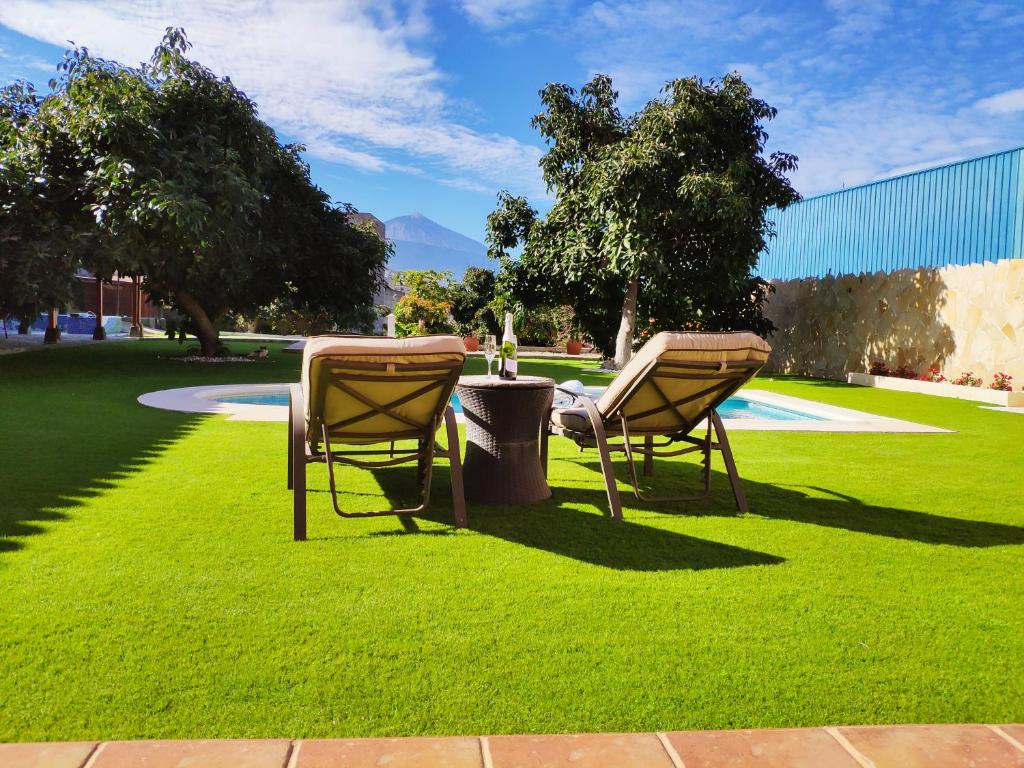 2 chaises assises sur l'herbe dans un parc dans l'établissement Villas Norte Piscina privada climatizada, à La Victoria de Acentejo
